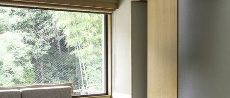 Una habitación tradicional japonesa con suelo de tatami, una mesa baja, un sofá y una silla.