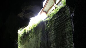 Eingang einer Höhle mit Blick auf ein traditionelles Gebäude durch einen natürlichen Bogen.