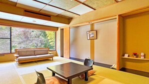 Ein traditioneller japanischer Raum mit Tatami-Böden, einem niedrigen Tisch, einer Couch und einer Schiebetür.