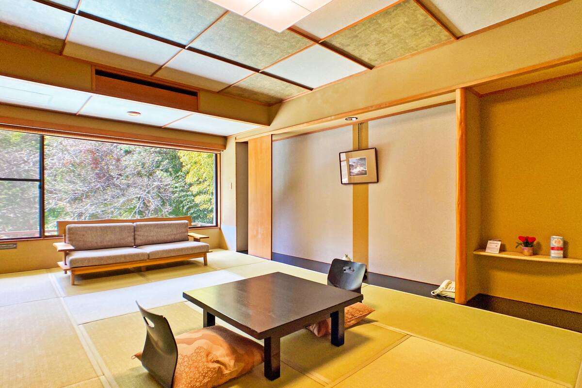 Habitació japonesa tradicional amb fons de tatami, una taula baixa, un sofà i una porta corredissa.