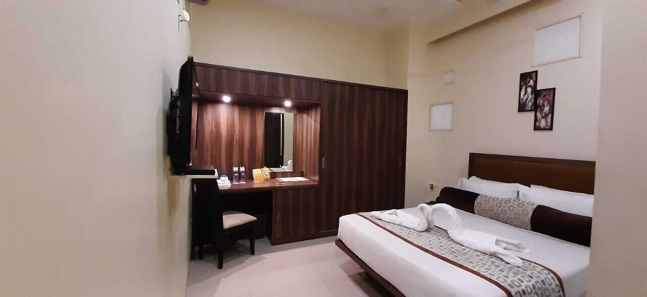 A hotel room with a bed, a desk with a mirror, and a television.