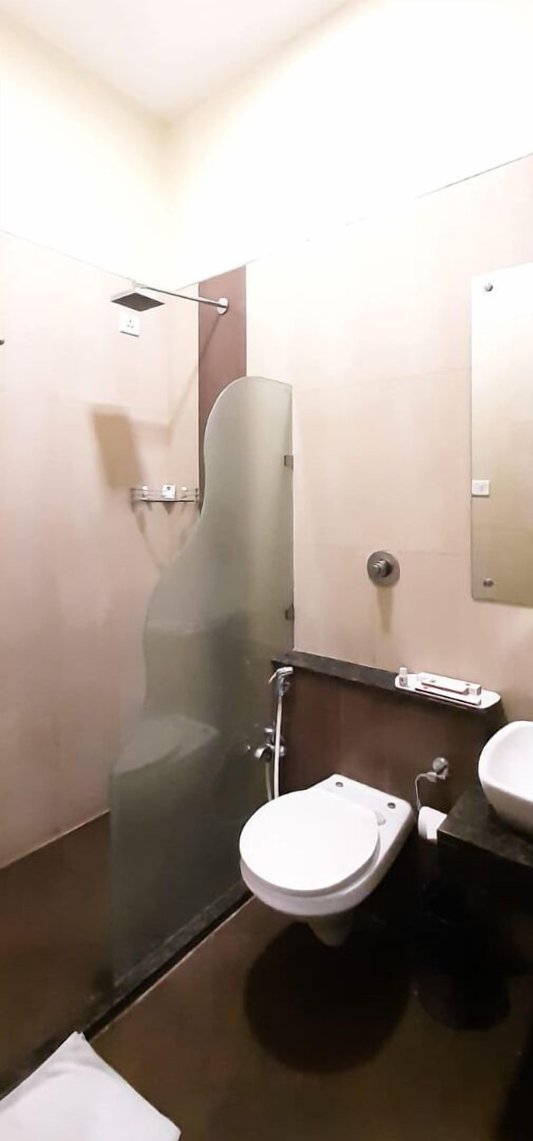 A bathroom with a glass-enclosed shower, a toilet, and a sink.