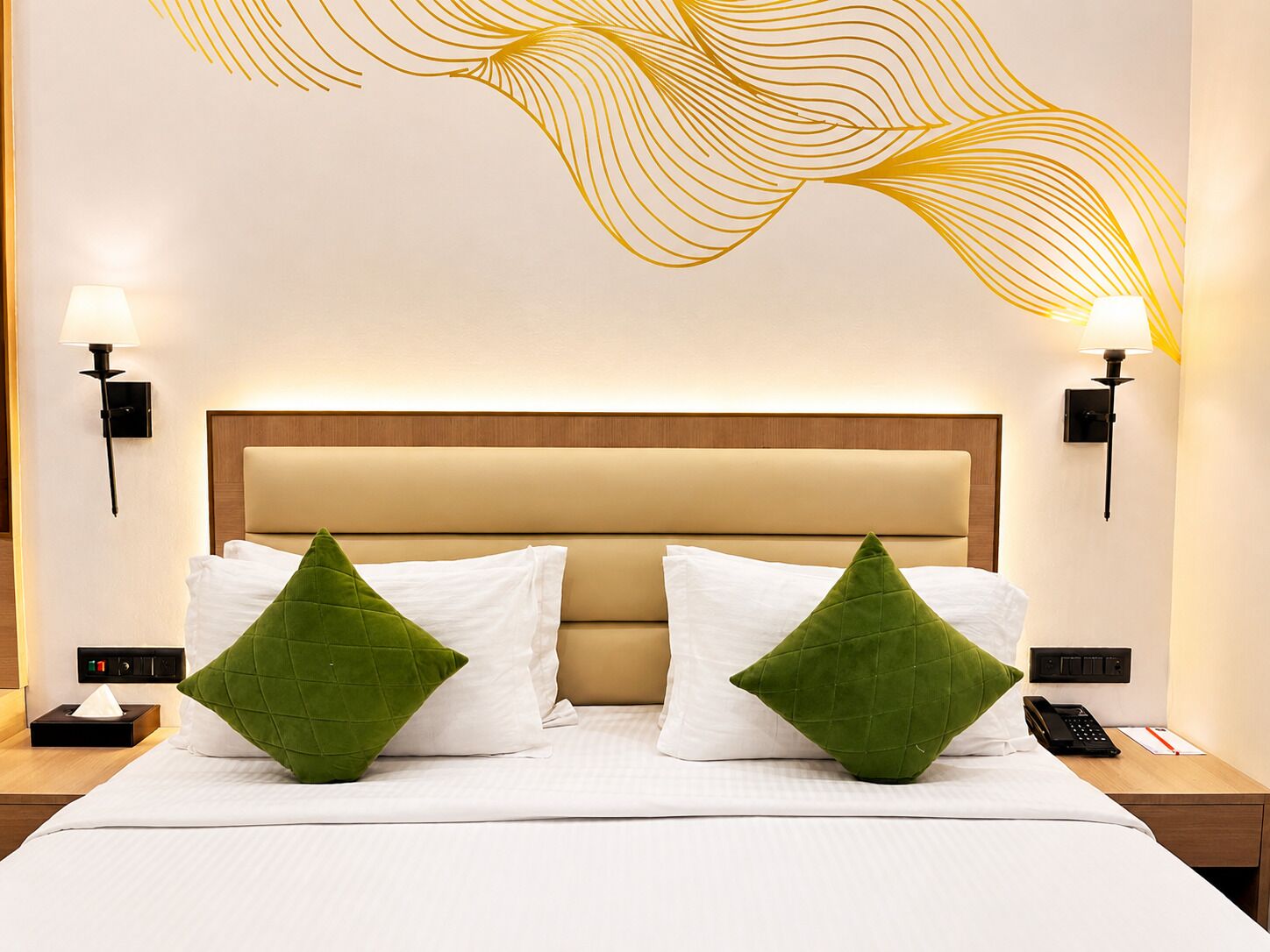 Une chambre d’hôtel comprenant un lit, deux tables de chevet, un téléphone fixé au mur et un motif décoratif sur le mur.