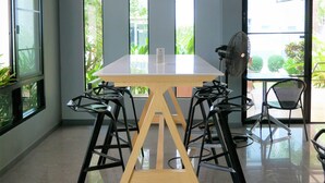 A modern dining area with a large table, black chairs, and a ceiling fan. - Villa's Day (Phitsanulok)