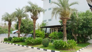 A modern building with a white exterior, surrounded by a well-maintained garden with palm trees and various shrubs. - Villa's Day (Phitsanulok)