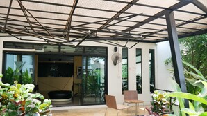 A modern building with a covered entrance, a reception desk, and seating area with chairs and tables. - Villa's Day (Phitsanulok)