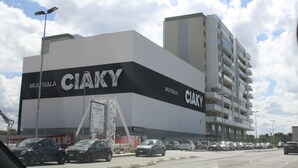 Ein Gebäude mit einem großen 'CIAKY'-Schild, einem Parkplatz und einer mehrstöckigen Struktur im Hintergrund.
