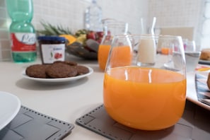 Une table de petit-déjeuner avec un verre de jus d’orange, une assiette de biscuits et une bouteille de soda.