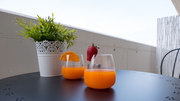 Two glasses of orange juice on a table with a potted plant beside them. - B&B Airport Bari - Palese (Bari)