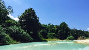 A river with clear water, surrounded by dense greenery and trees. - Agriturismo Le Cascatelle (Manciano)