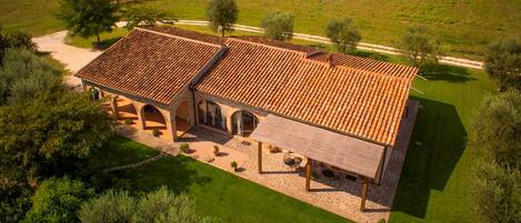 A large, two-story building with a tiled roof, surrounded by a well-maintained lawn and trees.