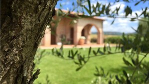 A building with a red facade and an arched entrance, surrounded by greenery. - Agriturismo Le Cascatelle (Manciano)