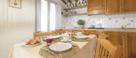 Un comedor con una mesa dispuesta para el desayuno, incluyendo cruasanes y un vaso de jugo.
