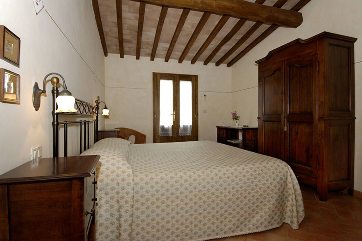 Une chambre à coucher avec un lit en bois, une table de chevet, une commode et une armoire.