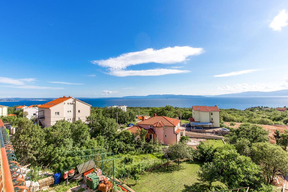 Ein Wohngebiet mit Häusern, blauem Himmel und Blick auf das Meer.