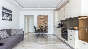 A modern kitchen with white cabinets, a brick accent wall, and a dining area with a table and chairs. - Luxury Apartments Kostrena (Kostrena)