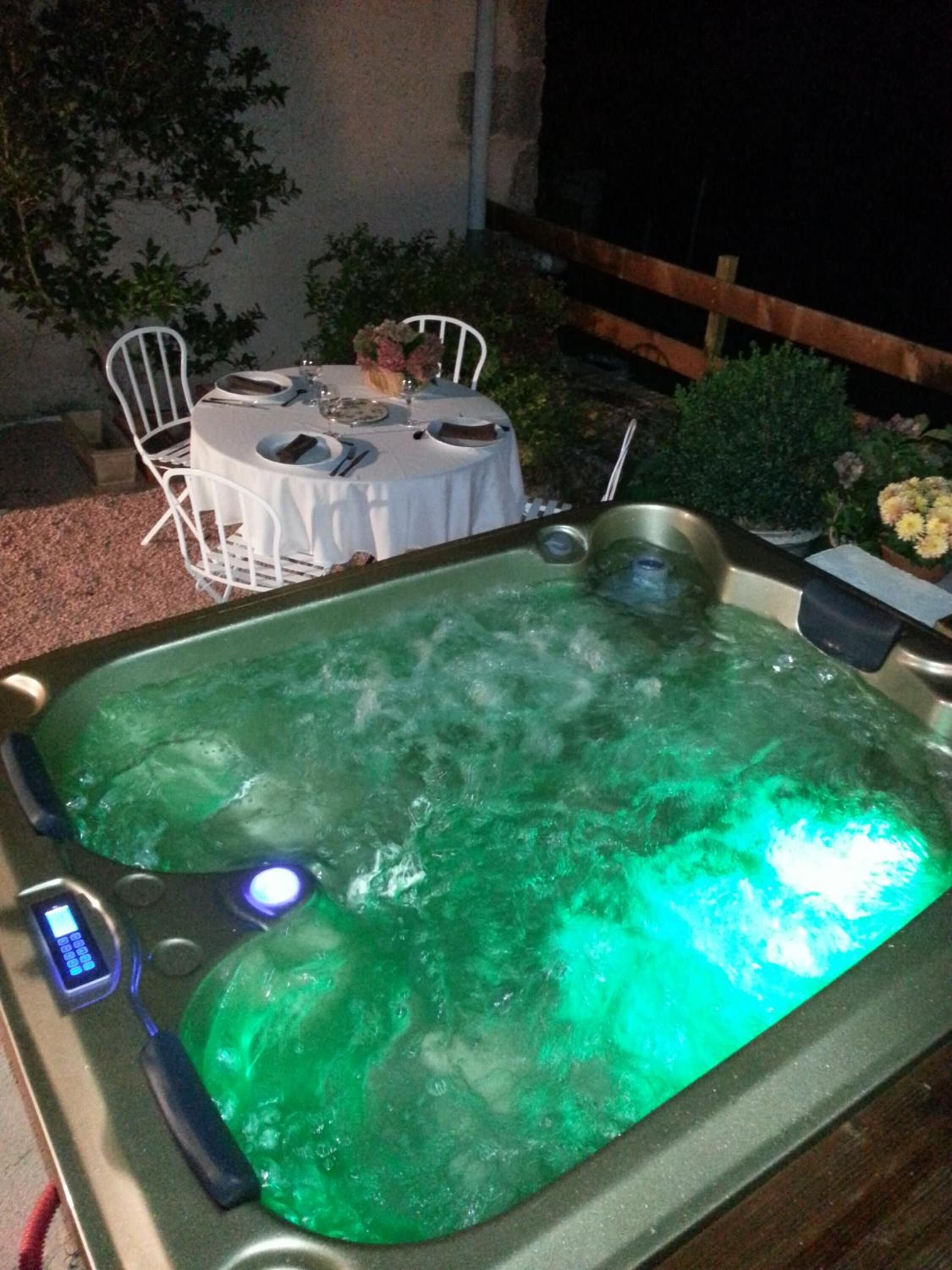Un jacuzzi con panel de control, rodeado de mobiliario exterior y plantas.