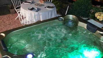 A hot tub with a control panel, surrounded by outdoor furniture and plants.