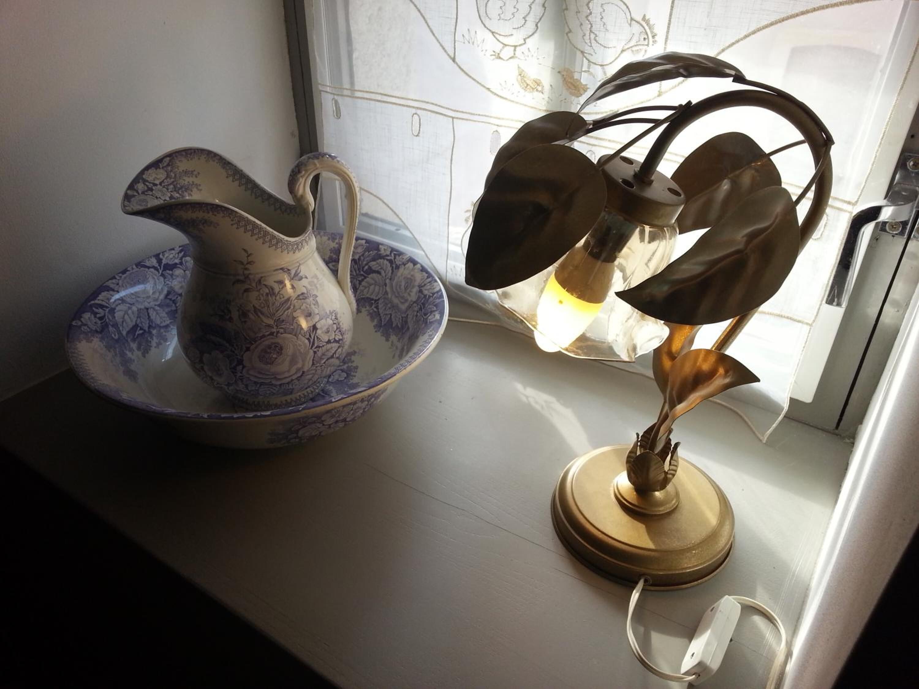 A decorative pitcher and a lamp on a table.