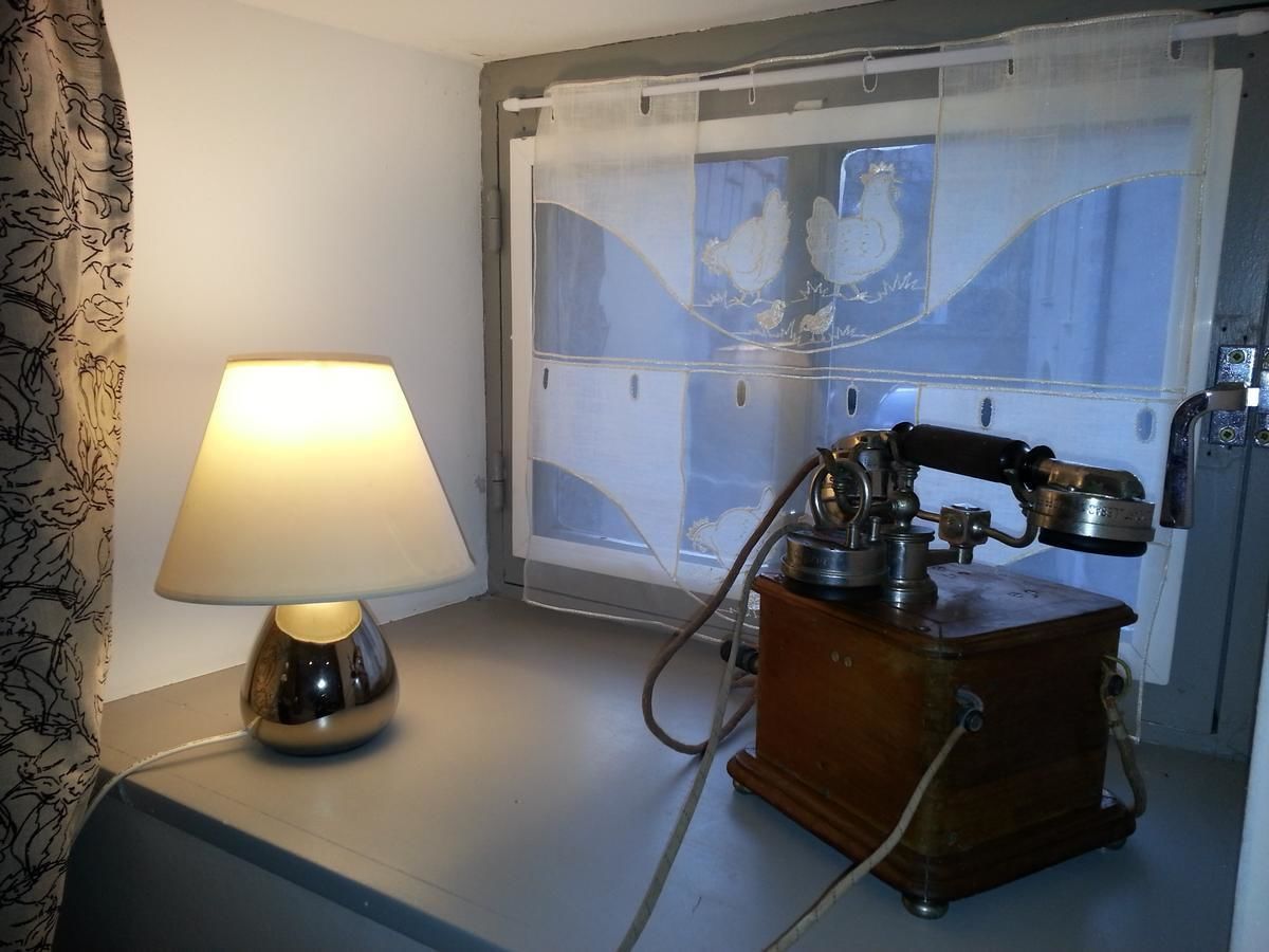 A room with a lamp, a vintage telephone, and a window with a view of chickens.