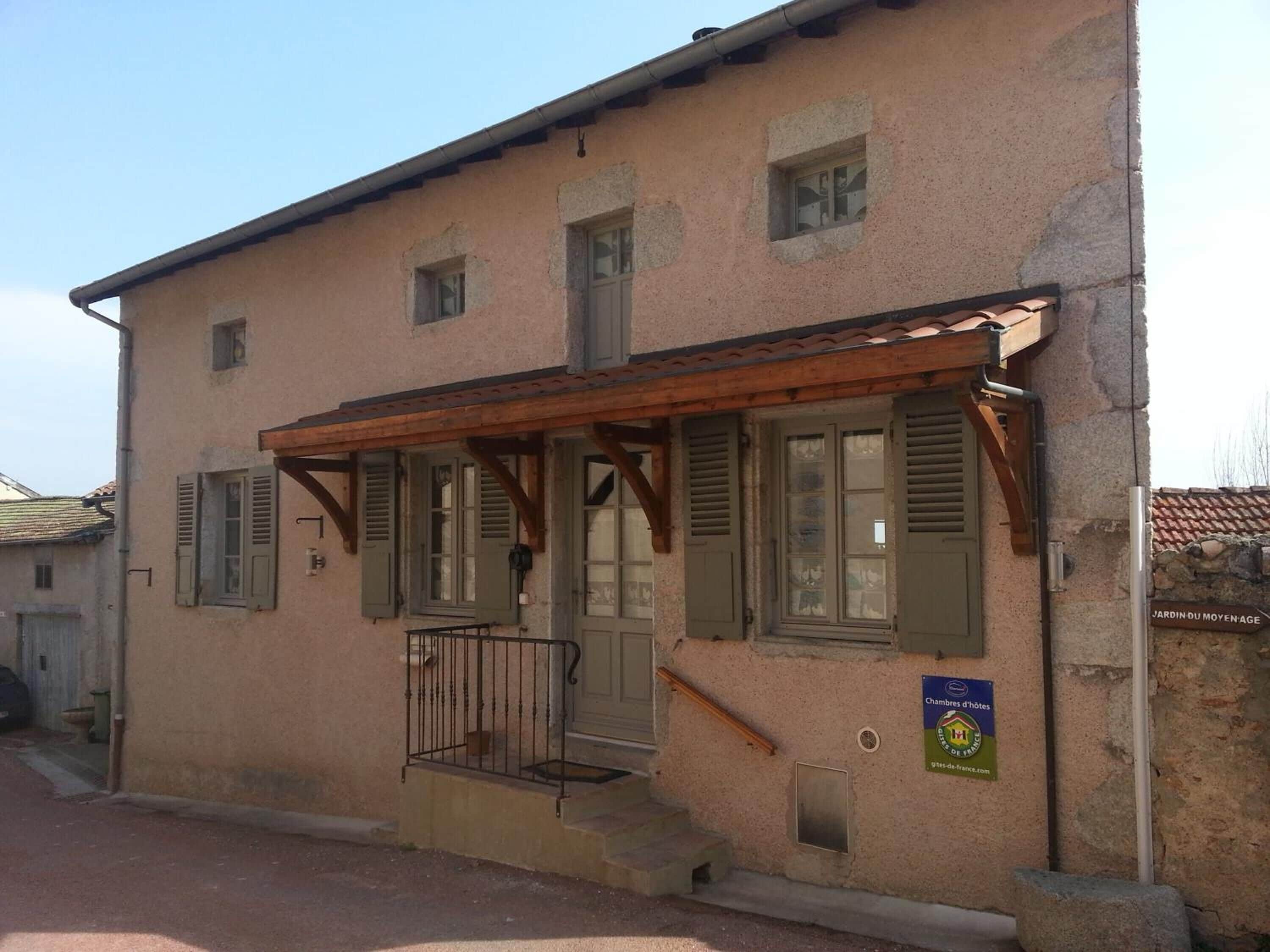 A two-story building with a wooden porch, green shutters, and a sign indicating it is a hotel.