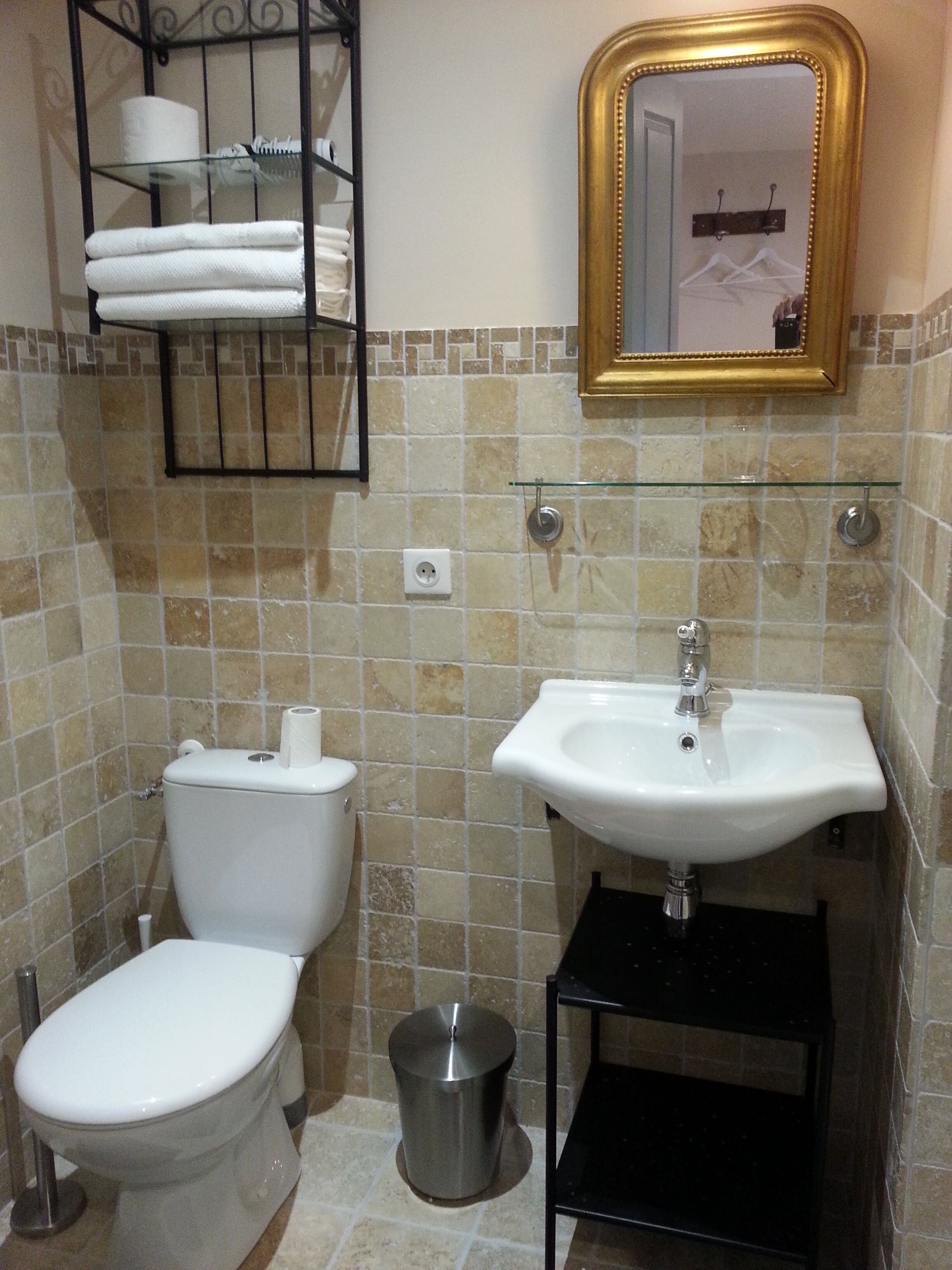 A bathroom with a toilet, sink, and a mirror with a gold frame.