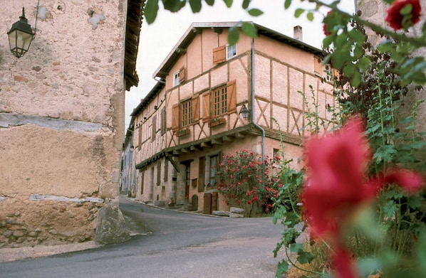 A narrow street with a building featuring a timber-framed facade and a stone wall on one side.