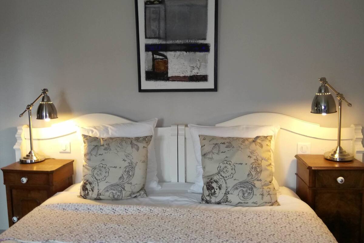 A neatly made bed with floral patterned pillows and two bedside lamps on wooden nightstands.
