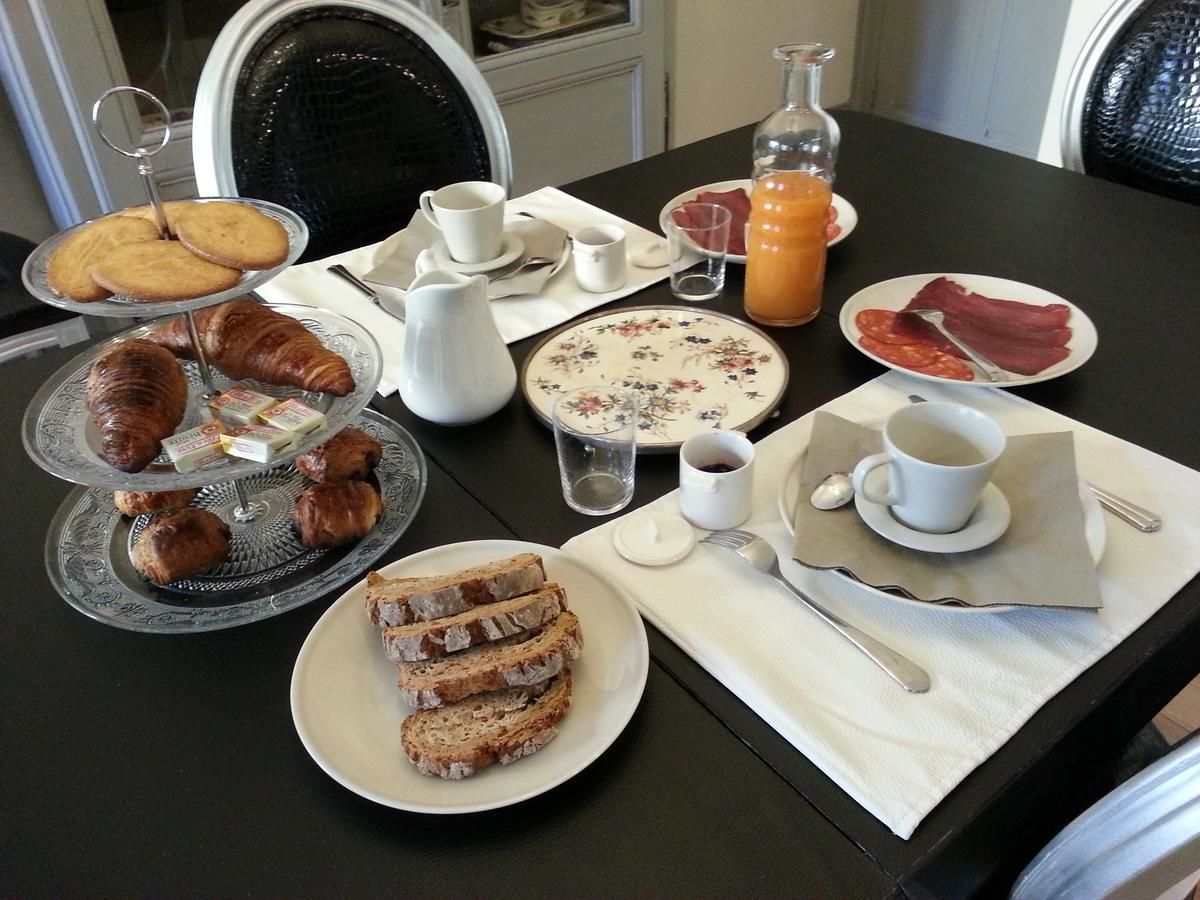 A breakfast table with croissants, bread, pastries, and a coffee cup.