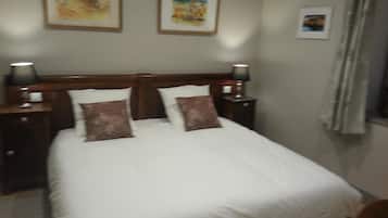 A neatly made bed with two pillows, a wooden headboard, and two bedside lamps.