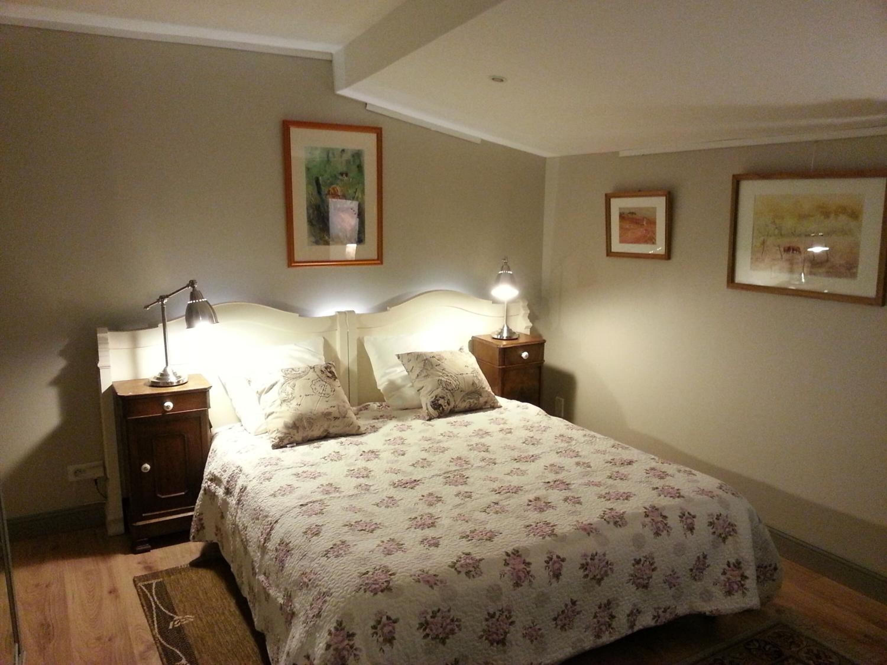 Une chambre à coucher comprenant un lit, deux tables de chevet et deux lampes fixées au mur.