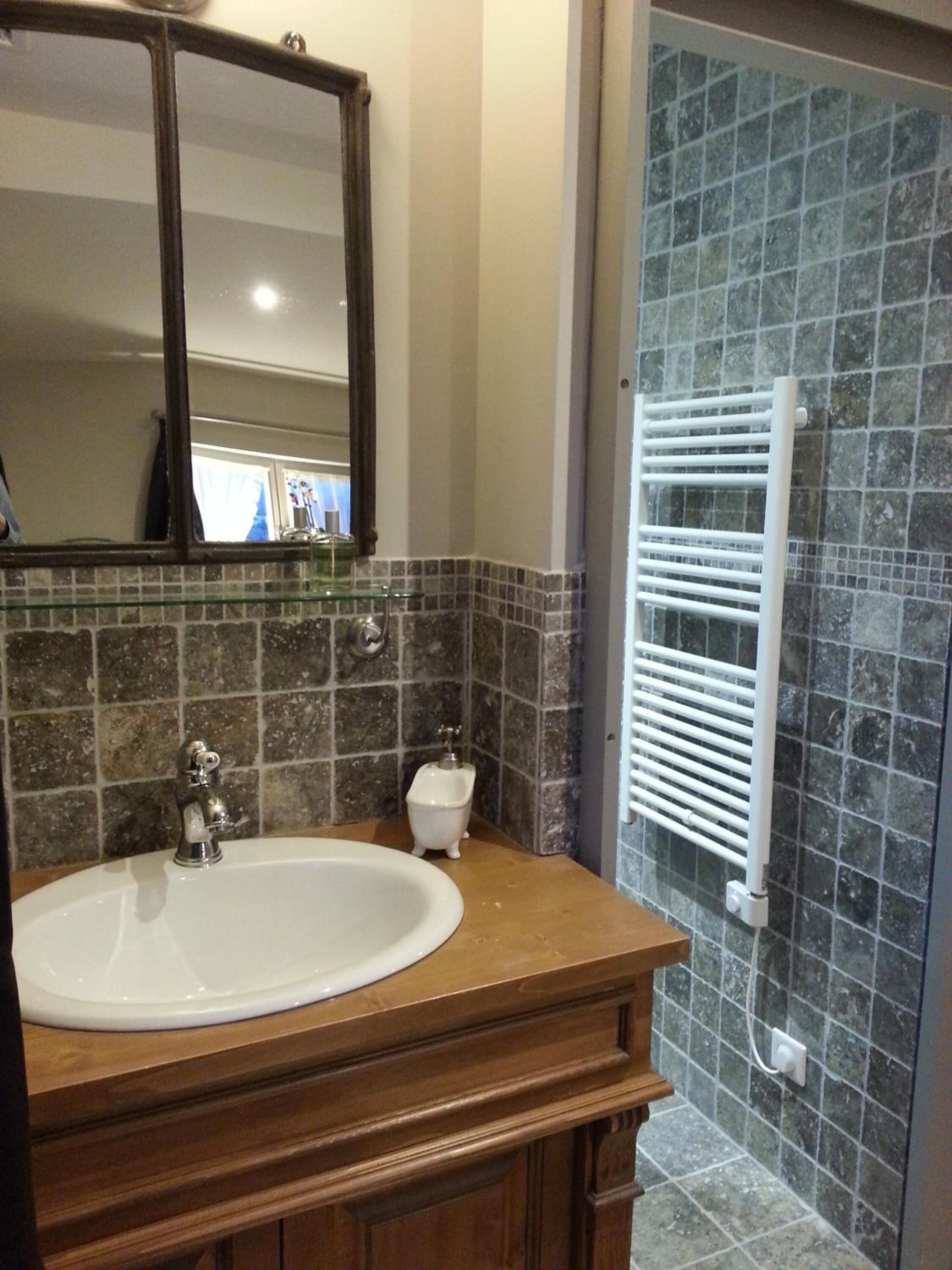 A bathroom with a white sink, a mirror, and a glass shower enclosure.