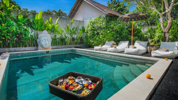 A swimming pool with a breakfast tray, lounge chairs, and a statue. - Villa Maviba Seminyak (Seminyak)