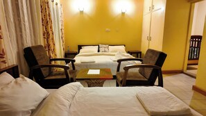 Una habitación de hotel con una cama, dos sillones, una mesita y una mesita de noche.