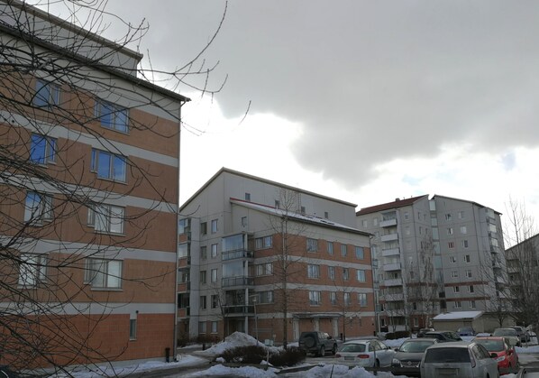 Un edificio residencial de varios pisos con un área de estacionamiento en la parte delantera.