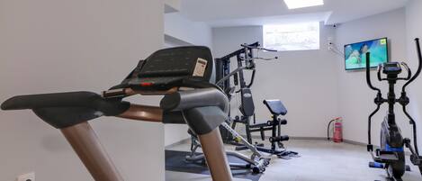 A gym with a treadmill, elliptical, and stationary bikes.