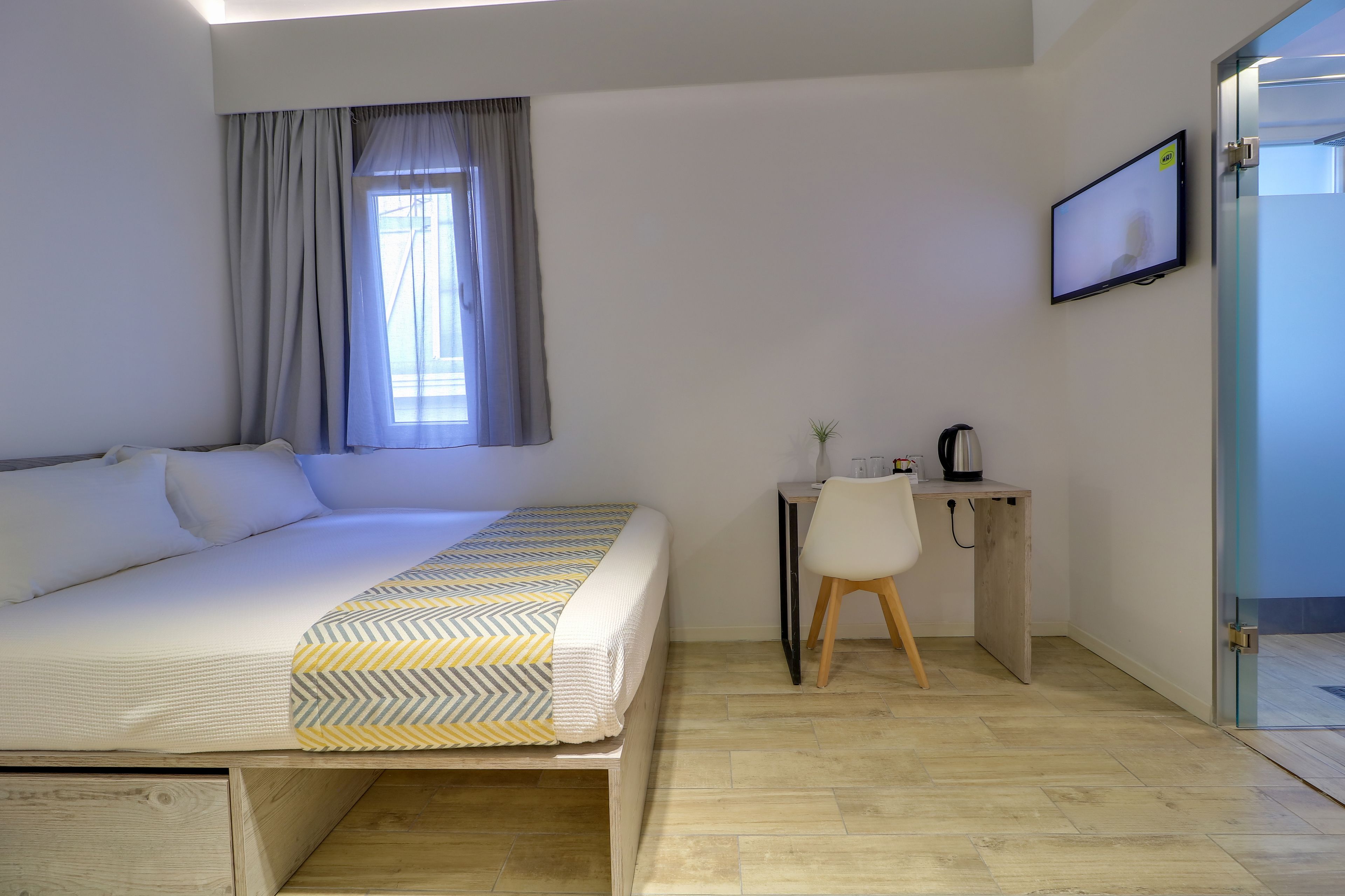 Une chambre d’hôtel avec un lit, un bureau, une chaise et un téléviseur.