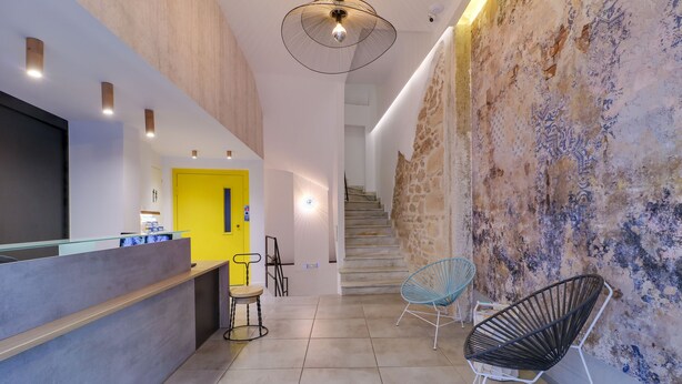 A modern reception area with a counter, a yellow door, and a staircase leading to another floor. - athensotel (Athens)