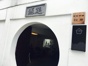 An entrance with a sign above it, a wooden plaque with a number, and a black sign with a logo. - Suzhou Suqilife Homestay (Suzhou)