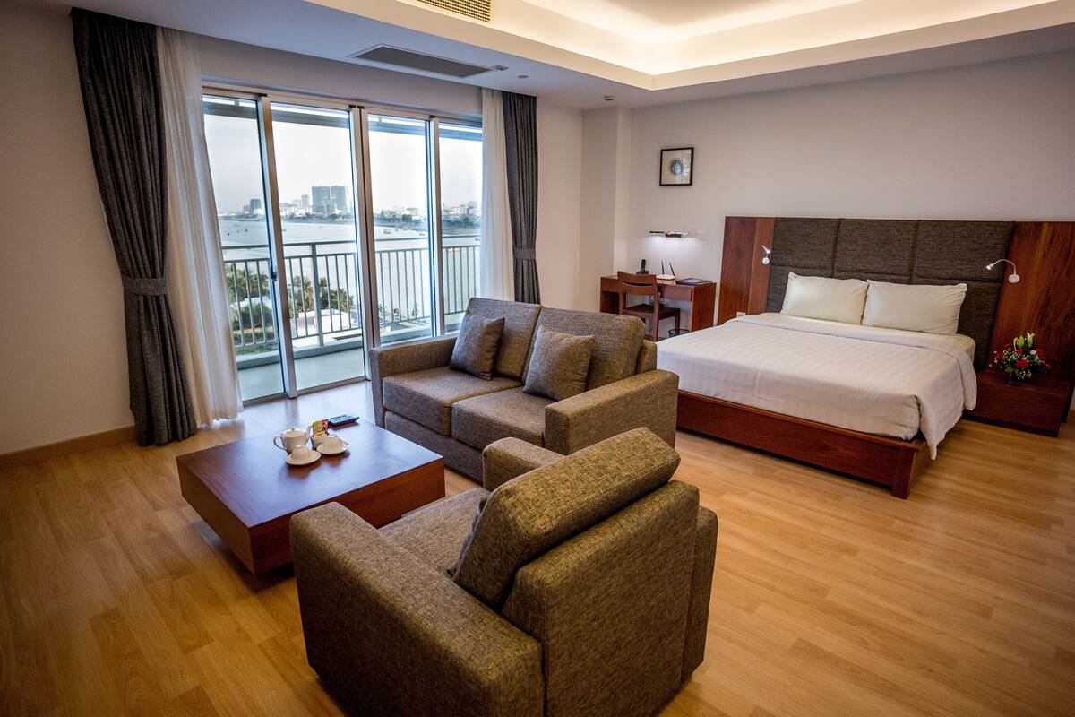 A hotel room with a bed, sofa, and a desk with a chair.