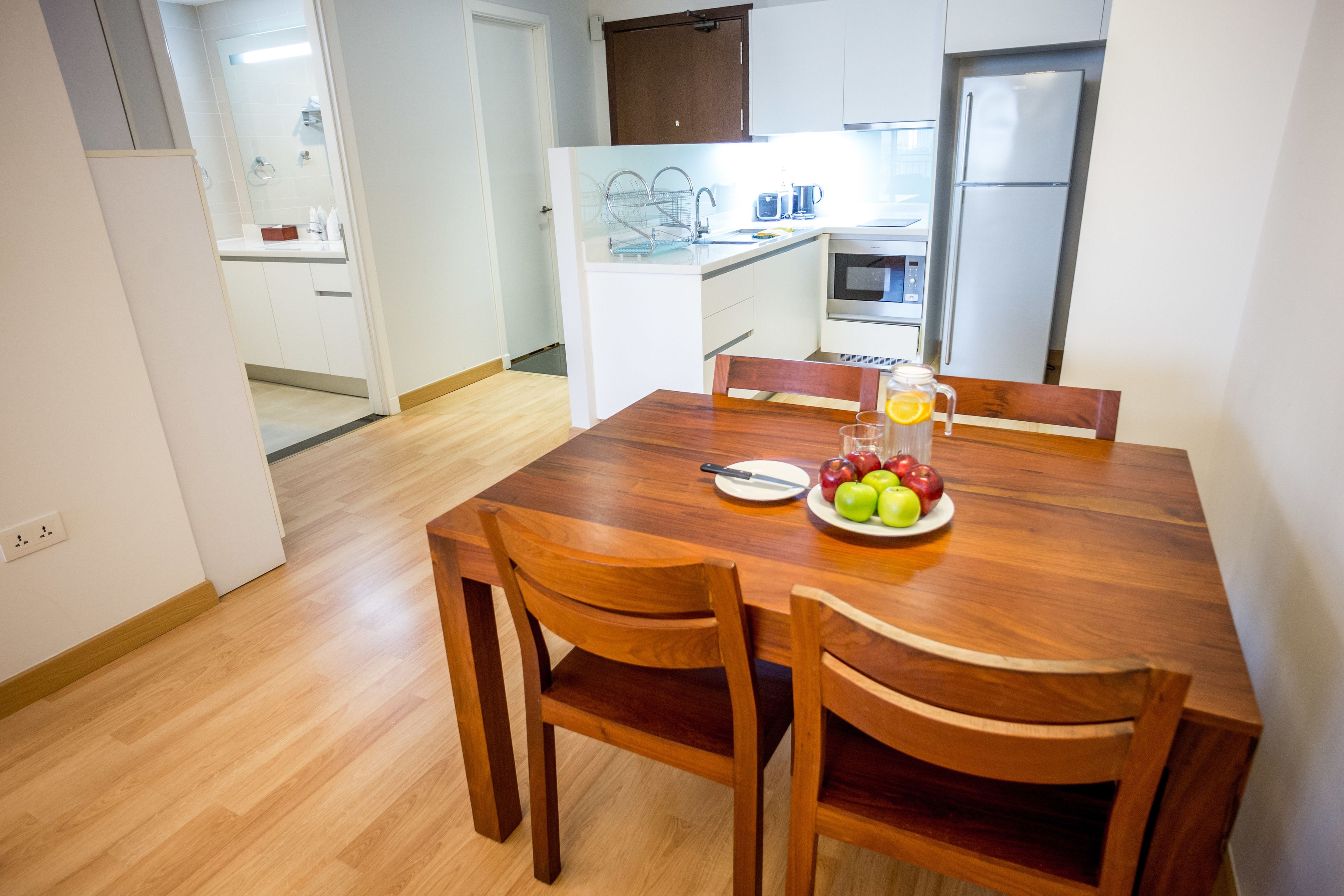 A dining area with a wooden table and chairs, a fruit plate, and a glass of orange juice.