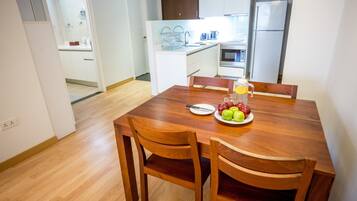 A dining area with a wooden table and chairs, a fruit plate, and a glass of orange juice.