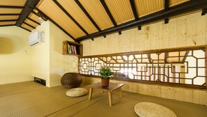 A tatami mat room with a wooden ceiling, a small table with a potted plant, and a woven stool. - Hemu Shantang Street (Suzhou)