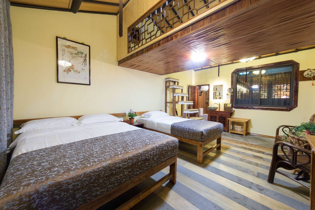 Una habitación con dos camas de madera, un escritorio de madera y una ventana al estilo tradicional chino.