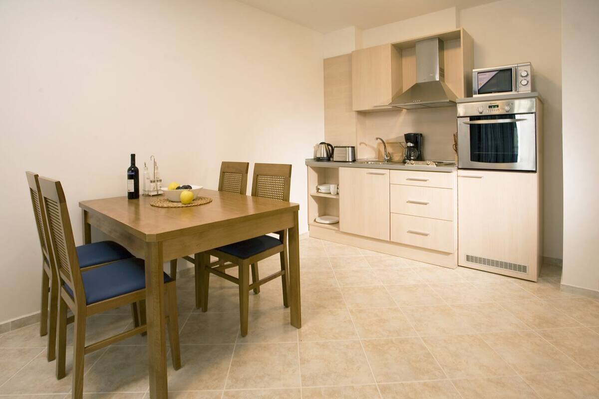 A compact kitchen with a dining table, chairs, a microwave, an oven, and a coffee maker.