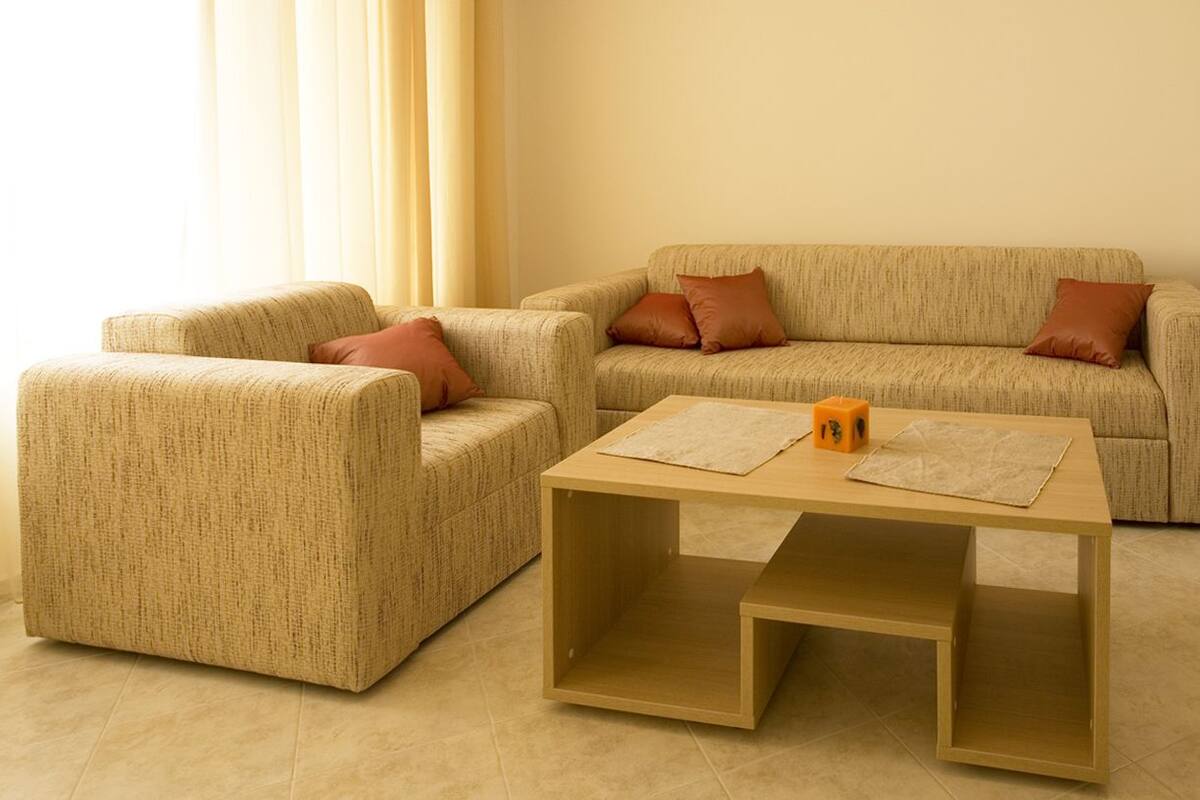 A living room with a beige sofa, two matching armchairs, and a wooden coffee table.
