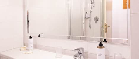 A bathroom with a large sink, a mirror, and a shower area.
