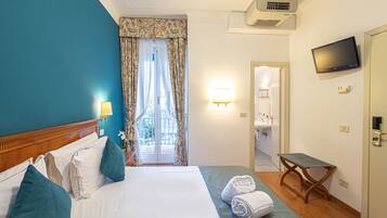Ein Hotelzimmer mit Bett, Fernseher, Schreibtisch und sichtbarem Badezimmer durch die Tür.