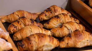 Diversa selecció de pastissos, incloent croissants i altres productes de forneria, disposats sobre una superfície de fusta.