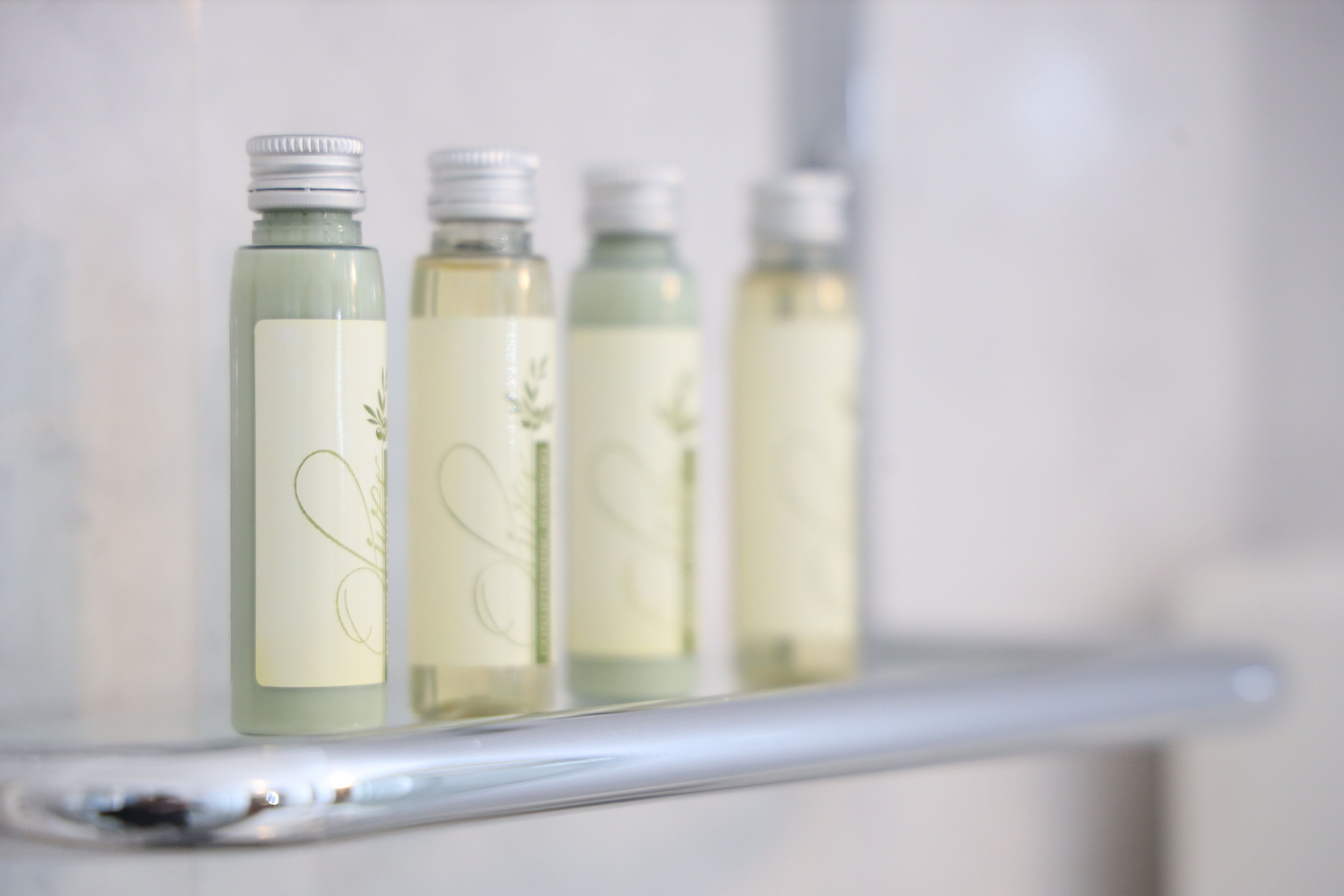 Four bottles of liquid on a white shelf.